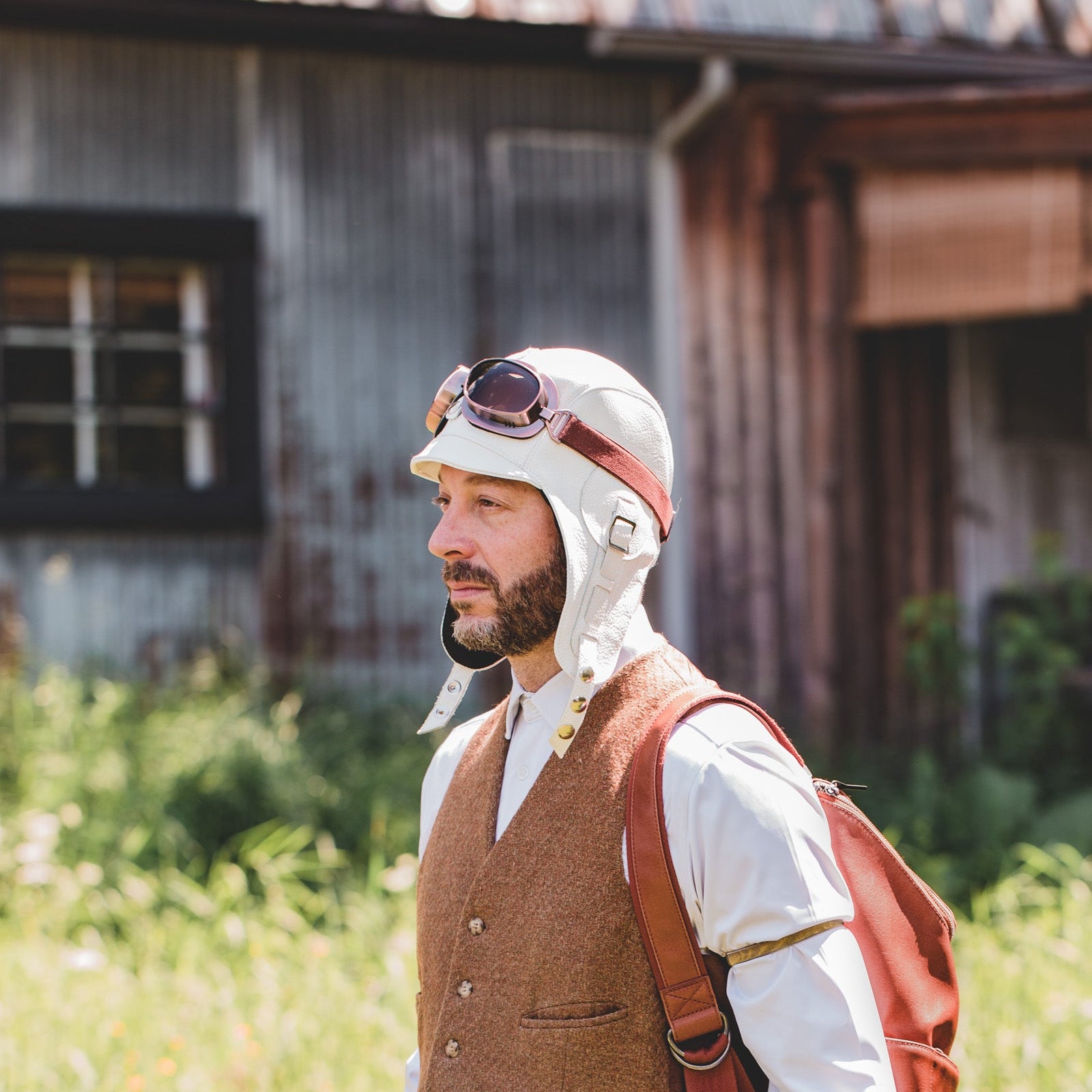 men in a filed wearing a white leather aviator hat