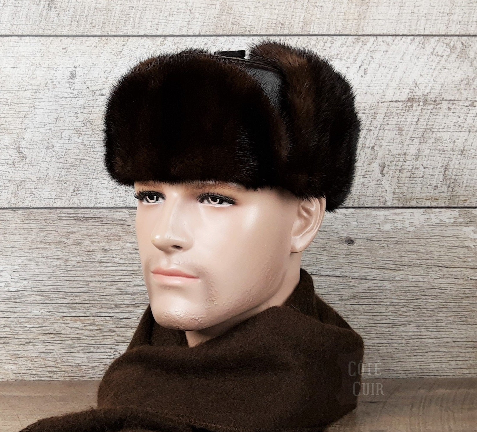 Man wearing a handmade leather and real fur chapka hat by Côté Cuir, standing in a Nordic winter landscape. Eco-friendly hat made in Canada with recycled fur.