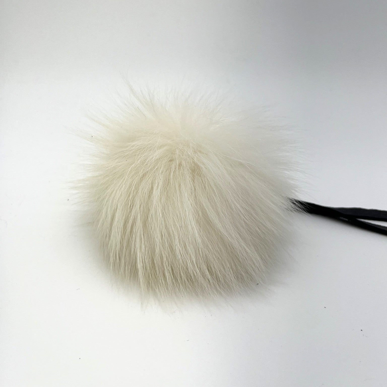 Genuine Norwegian fox fur pom-pom with leather tie strap. Handmade in Quebec. Luxurious volume and natural cream color with grey tips.